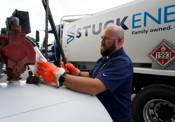 Stuck Energy technician operating a valve on top of a tanker
